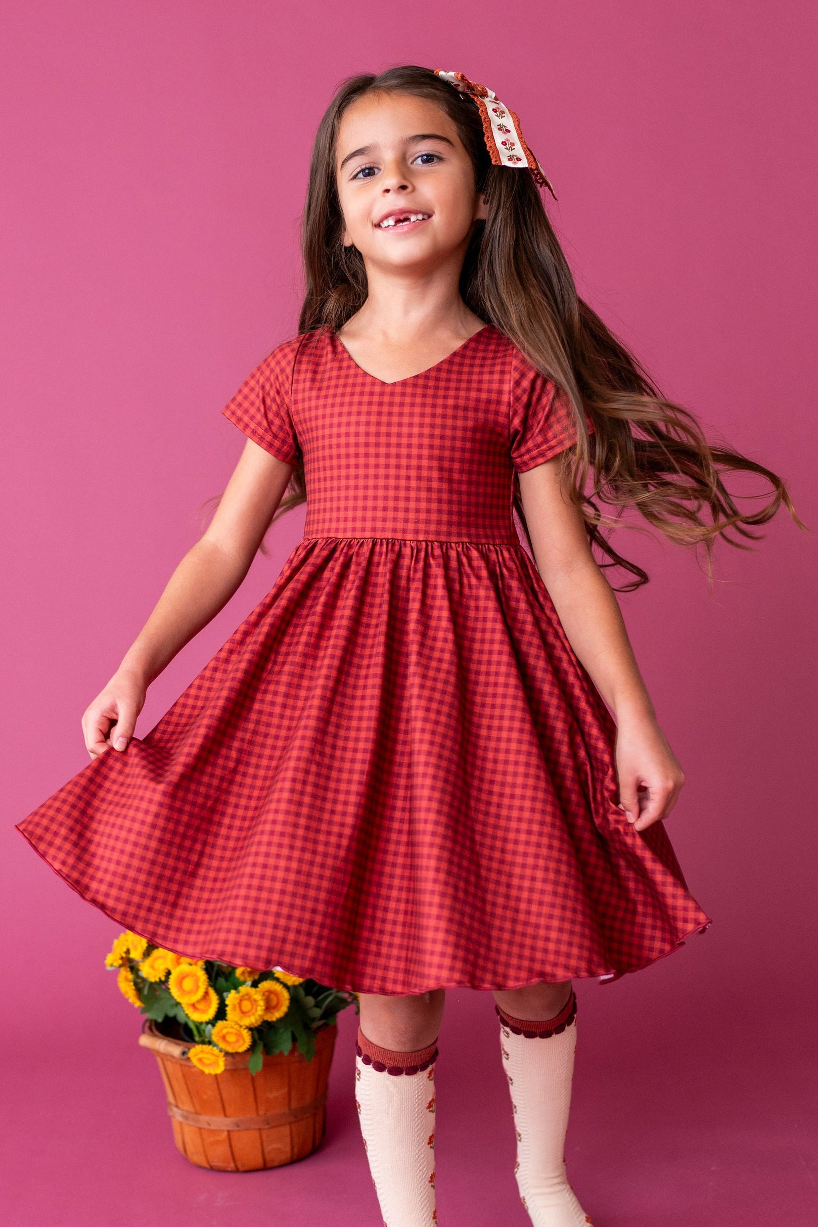 girl twirling in rust and burgundy dress with floral knee high socks
