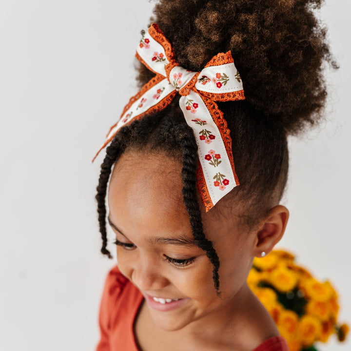 little girl in pony tail with rust and cream floral hairbow with lace trim