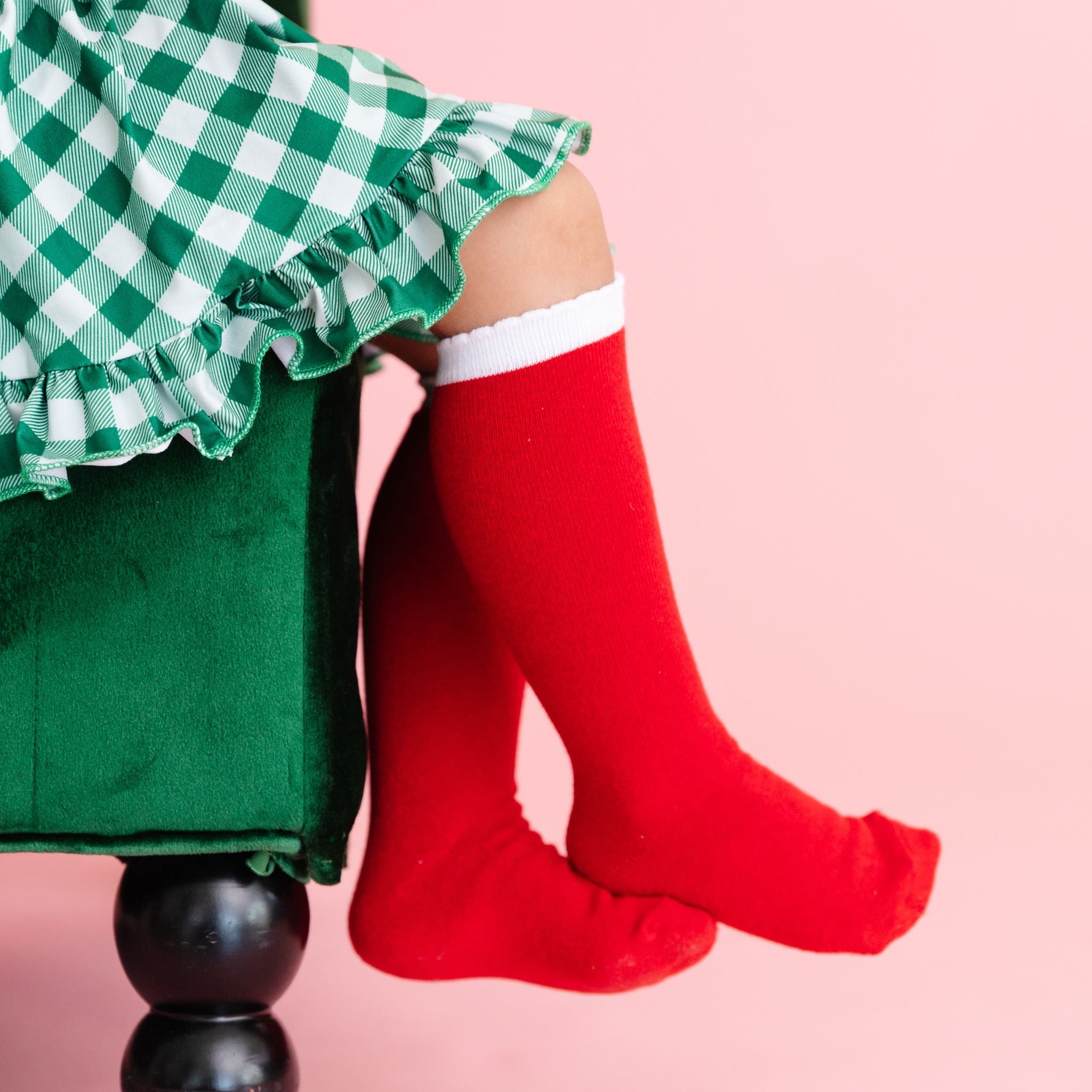 little girl in red and white Santa inspired tall socks with green gingham Christmas dress