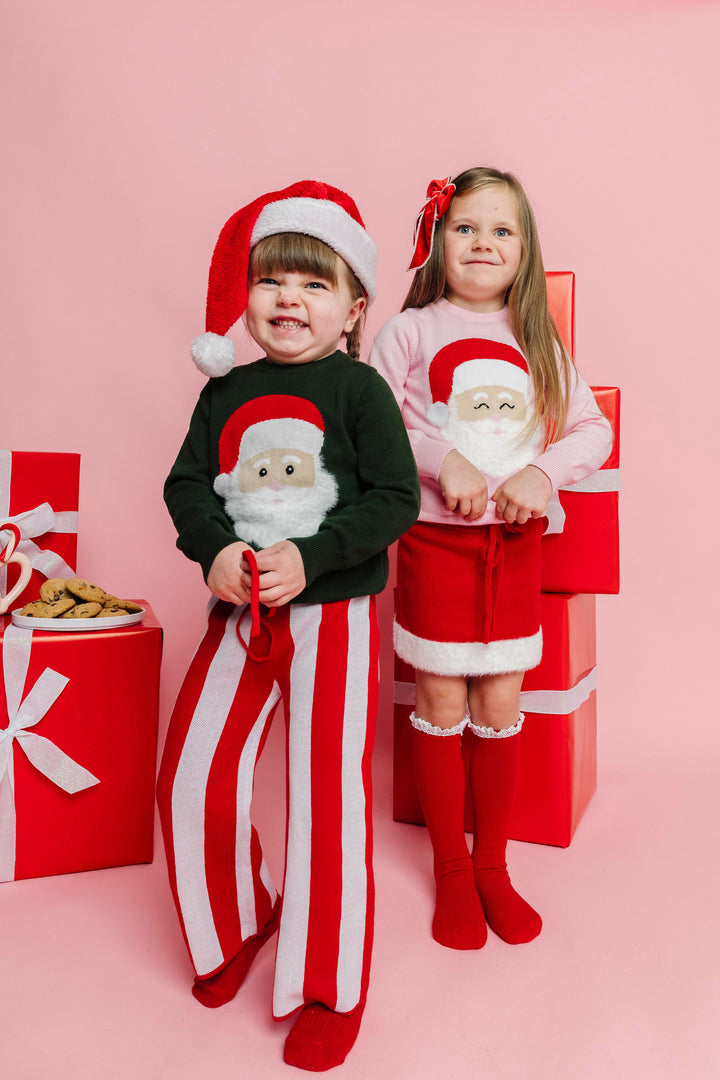 two girls in green and pink Santa sweaters with matching sweater pants and skirt for Christmas