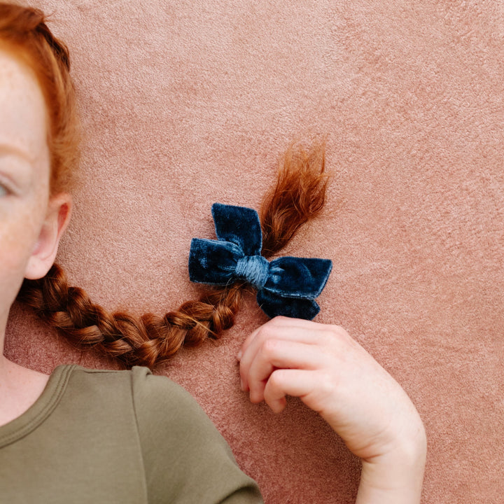 little girl with red hair and braided pigtails with blue velvet pigtail bows clipped in