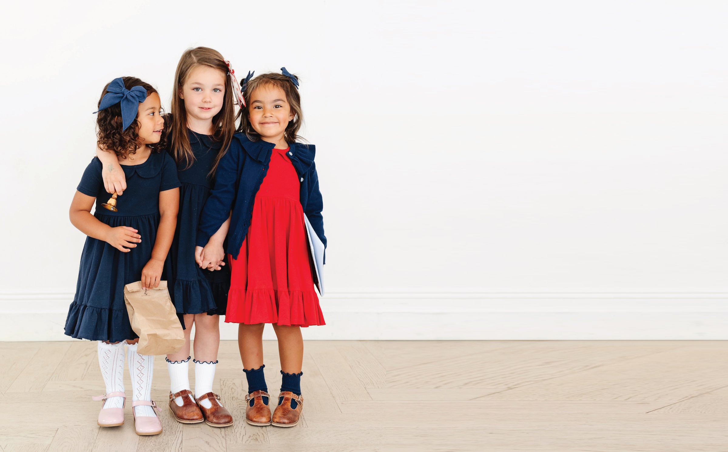 little girls in navy and red school uniform dresses and sweaters