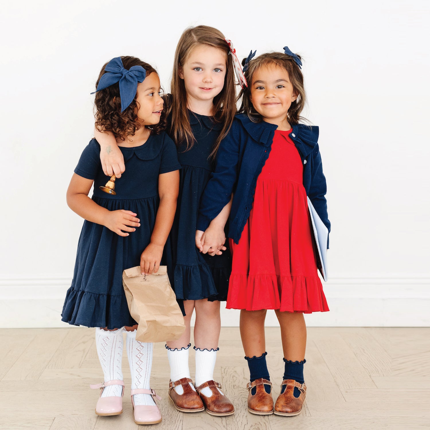 little girls in navy and red school uniform twirl dresses
