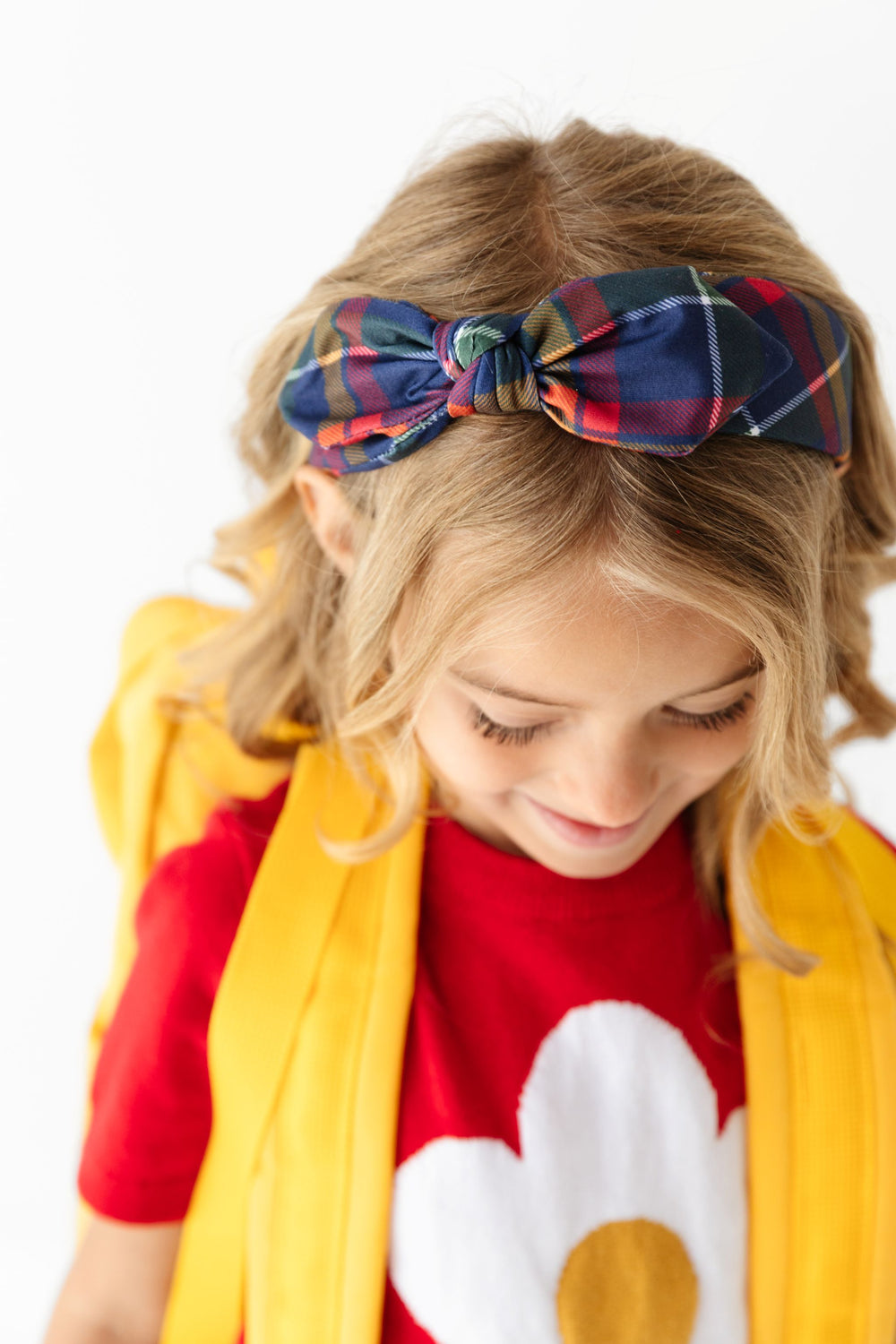 little girl with yellow backpack, red flower sweater and matching navy plaid knotted headband