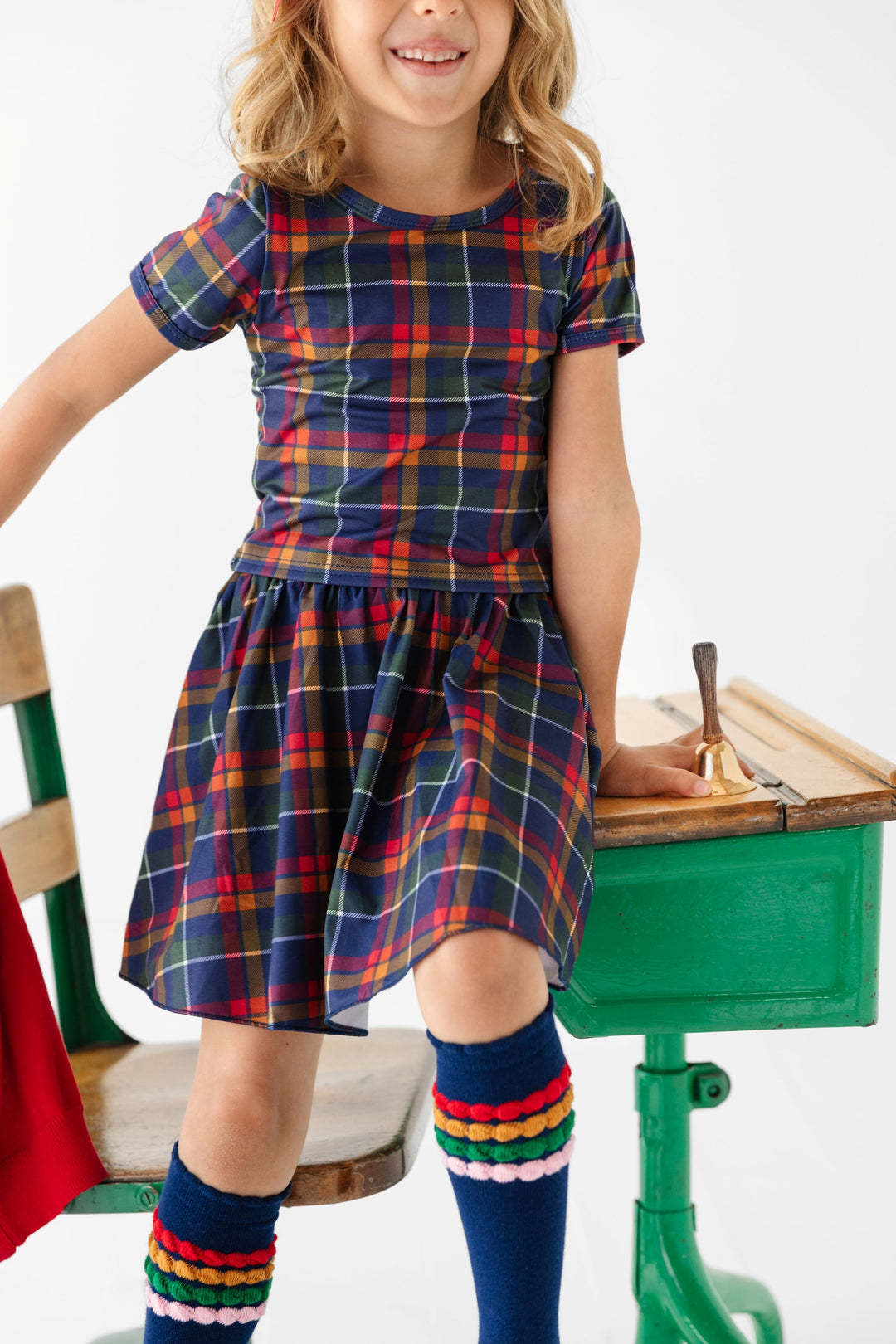 little girl in matching back to school plaid fitted t-shirt and skort set paired with navy knee highs with primary bubble stripe