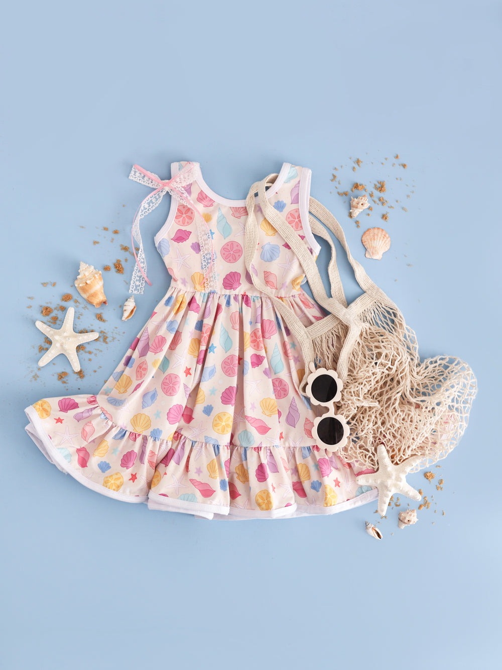 girl's sleeveless seashell print twirl dress styled with seashells and beach accessories 