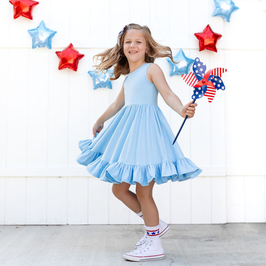little girl twirling in light blue cotton 4th of july dress with matching star socks