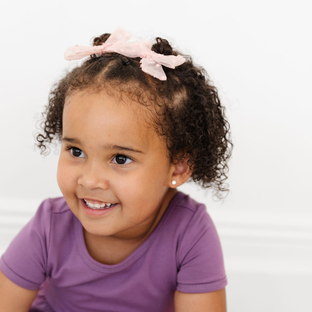 little girl in purple dress and light blush pink hair bows