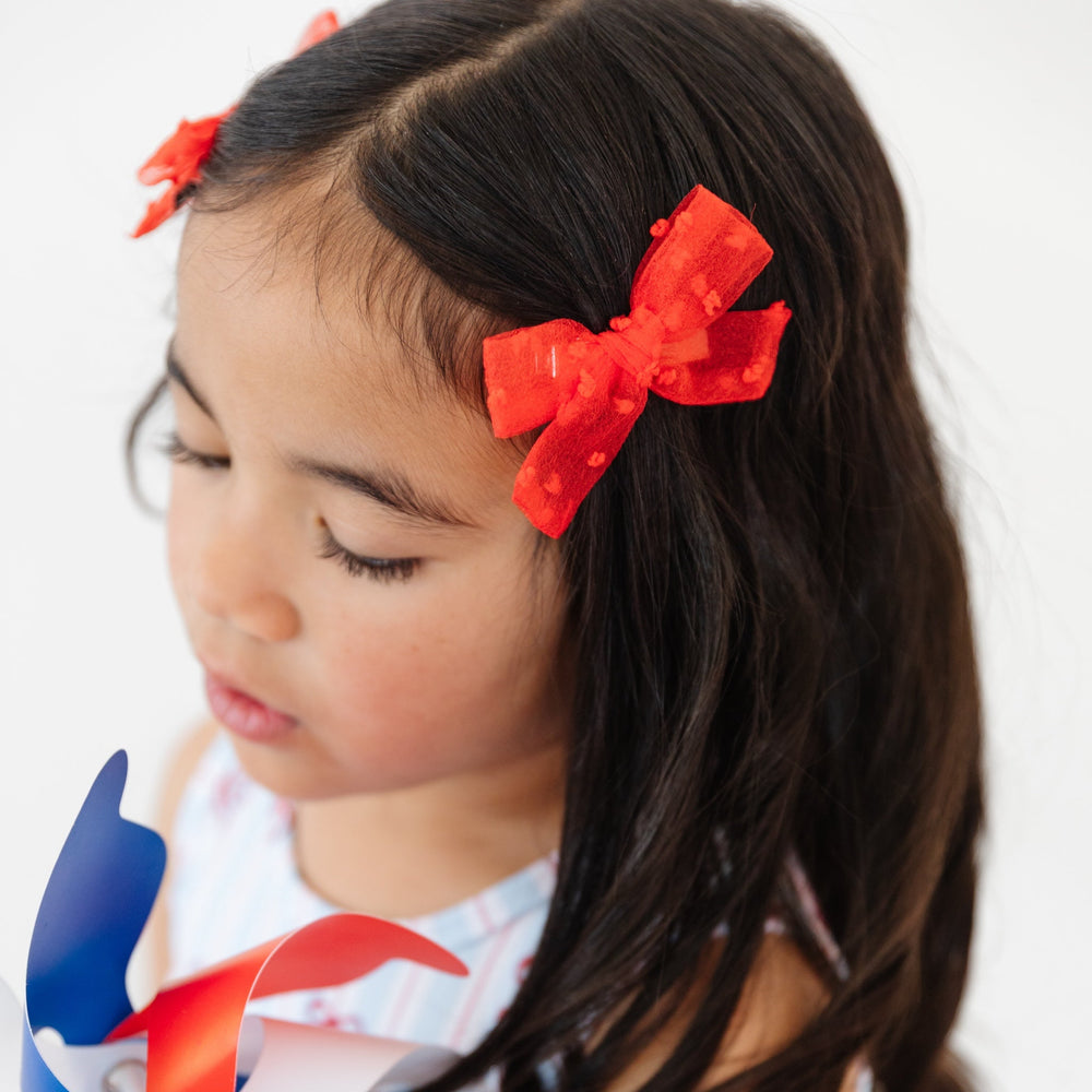 little girl wearing bright red sheer dot pigtail bows