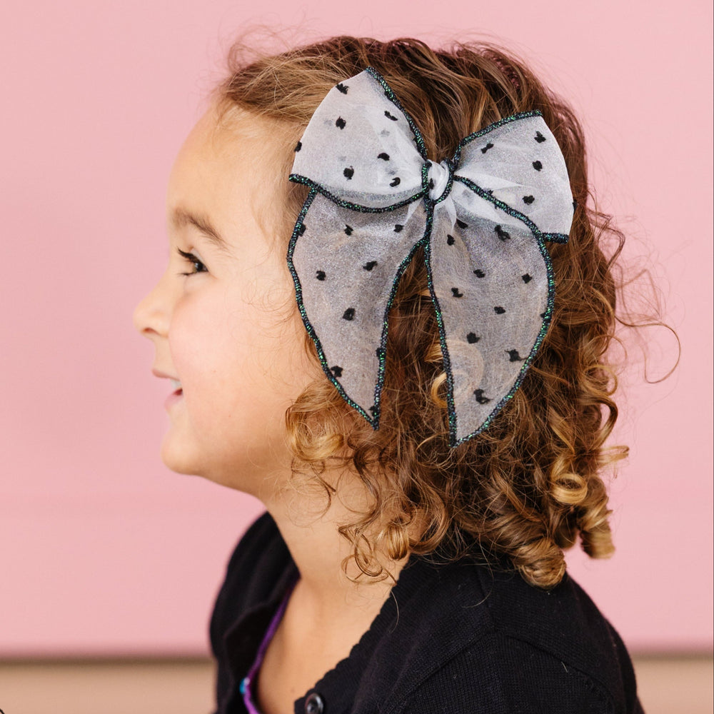 little girl in sheer Halloween bow with black dots and black sparkly trim