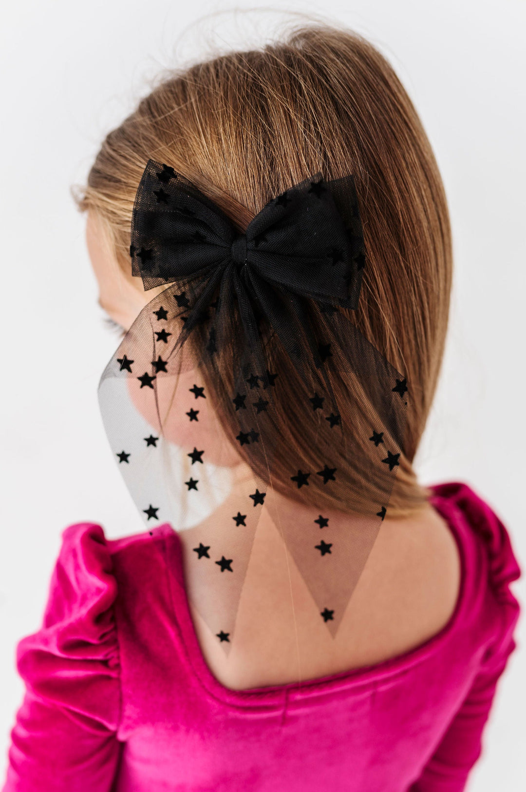 girl wearing hair bow made from sheer black fabric with flocked black stars