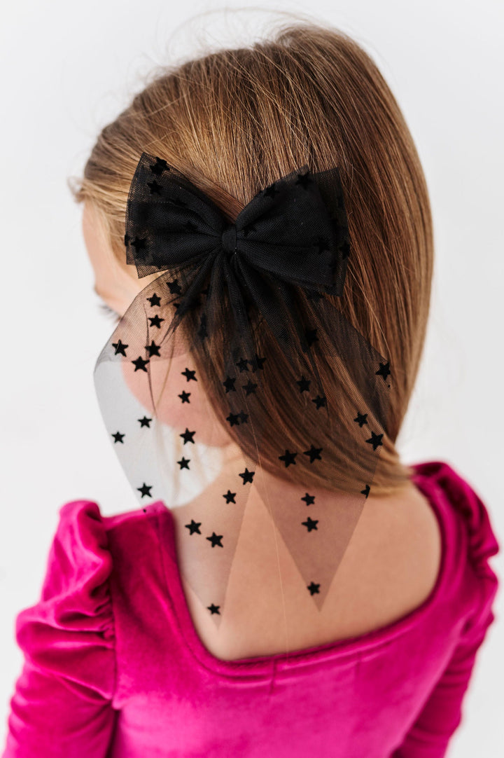 girl wearing hair bow made from sheer black fabric with flocked black stars