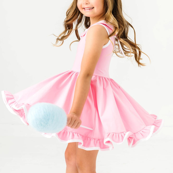 little girl twirling with cotton candy in pink sleeveless twirl dress with white binding