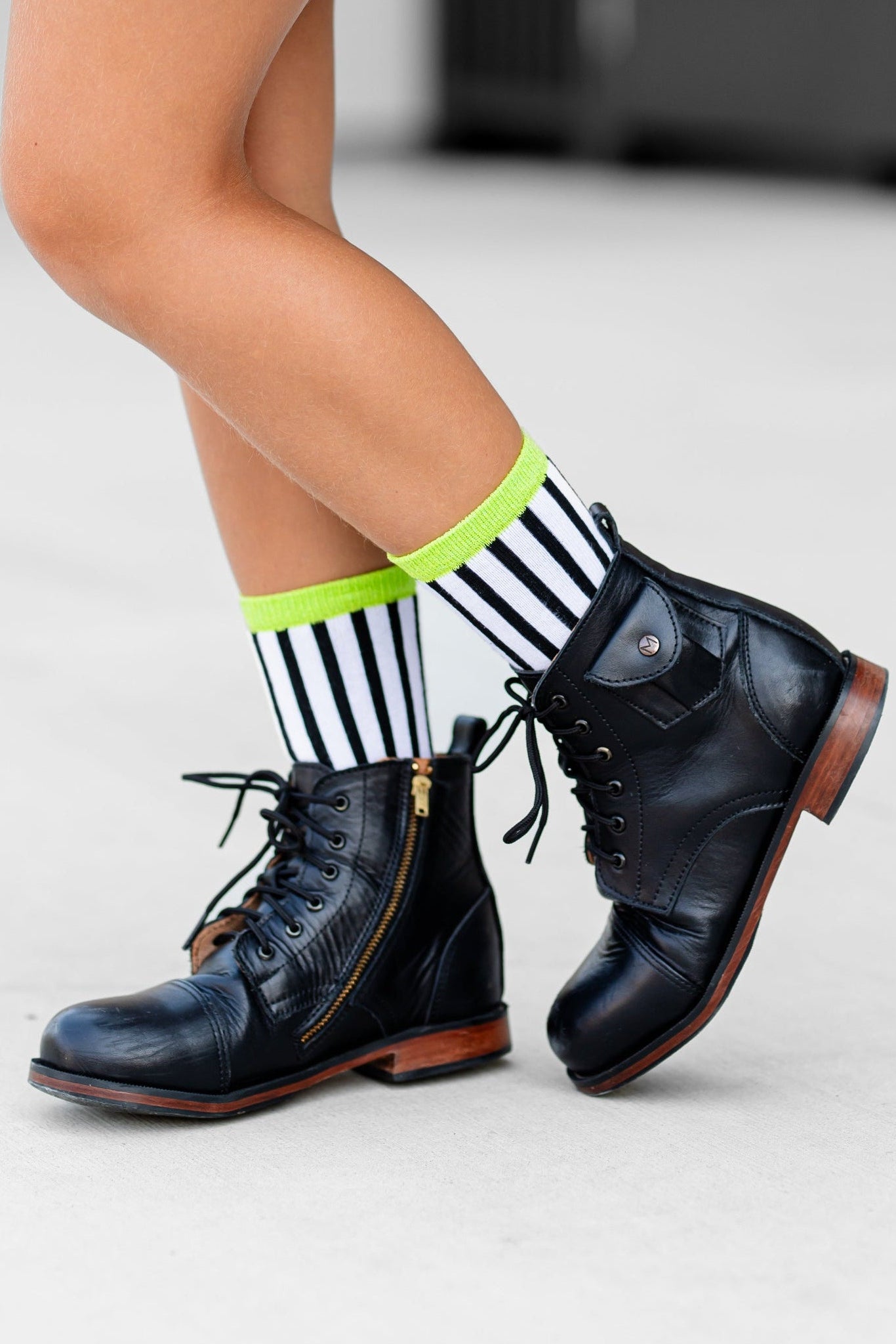 little girl in black sparkle tutu skirt pared with black and white striped midi socks with green sparkly trim and black boots for Beetlejuice inspired Halloween look