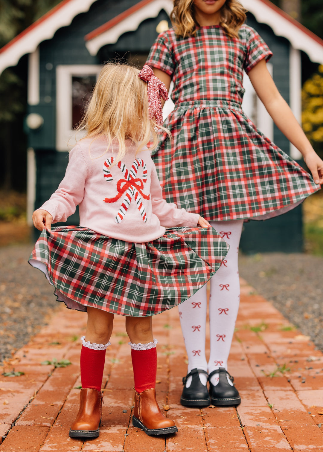 sister in matching Christmas plaid skirts paired with pink pullover sweater with vintage candy cane design and coordinating accesories