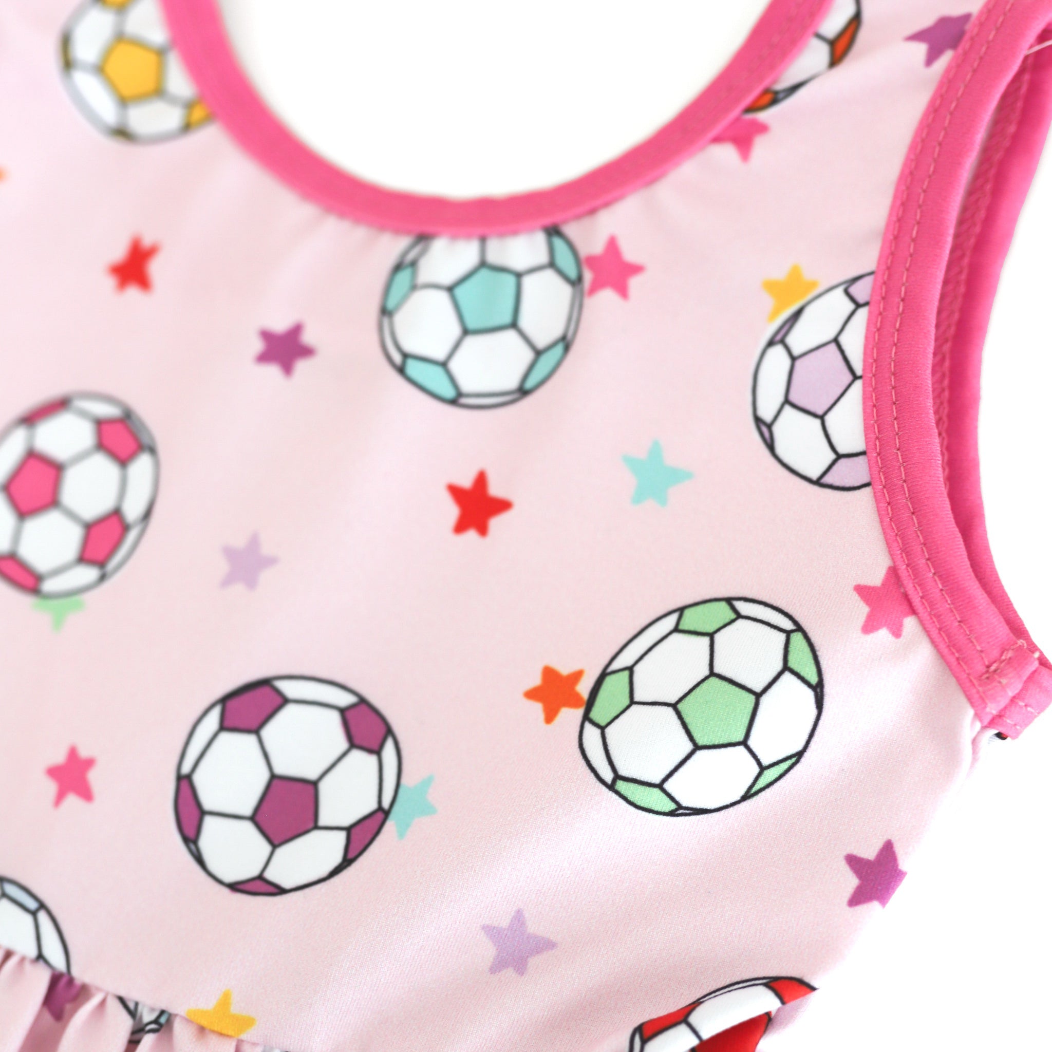 closeup of colorful soccer ball and petite star print on pastel pink dress bodice with bright pink trim