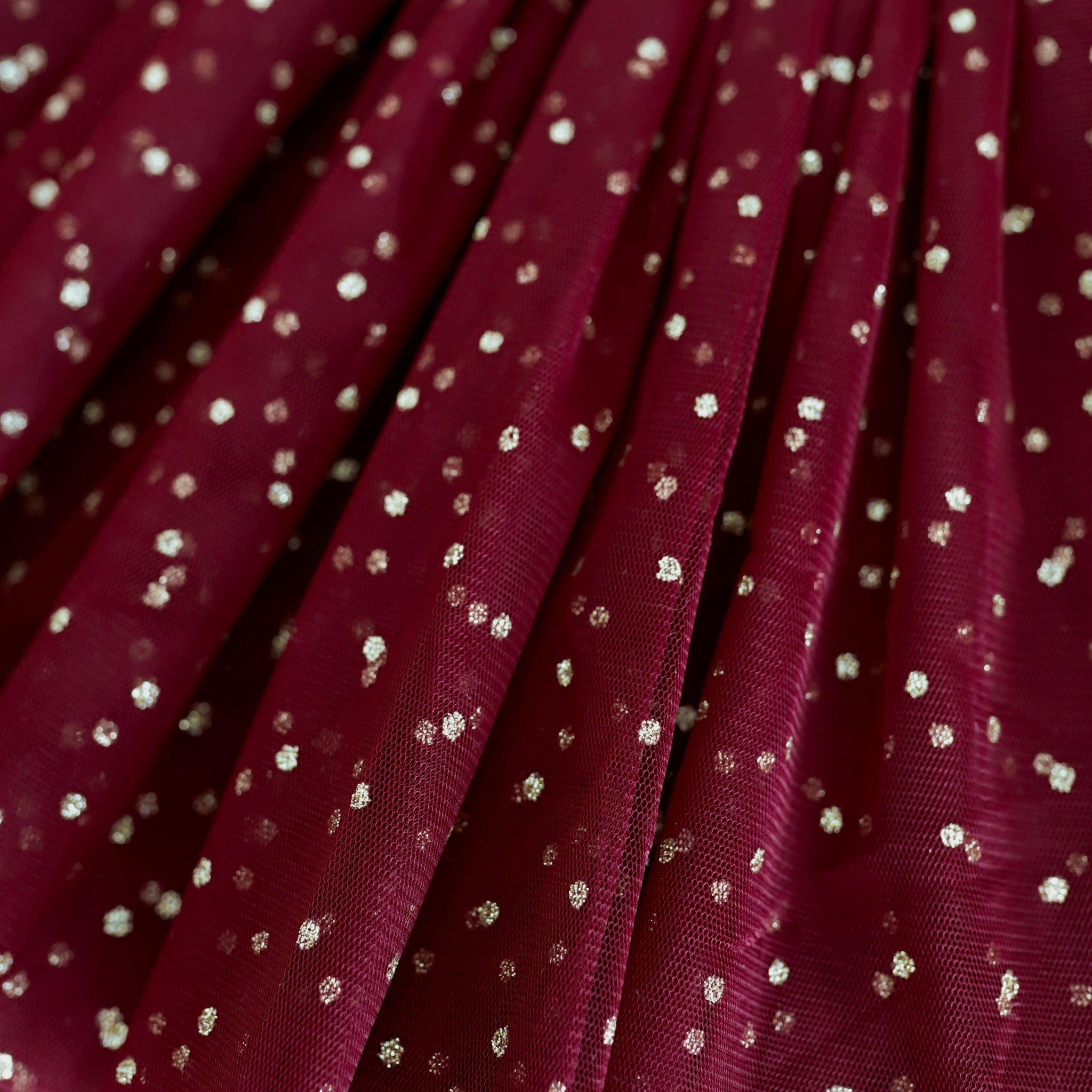 closeup of sparkly gold dots on crimson tulle