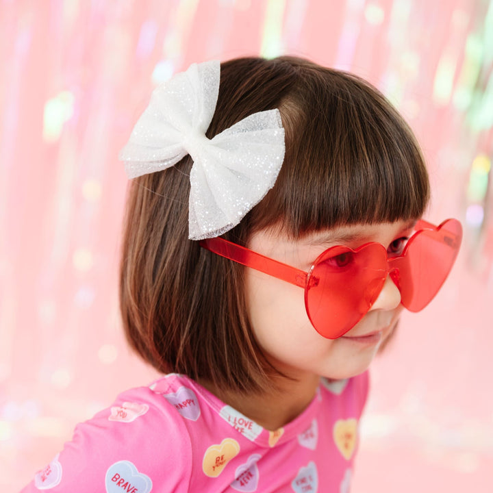 little girl in white sparkle tulle bow and heart sunnies to match conversation heart print dress