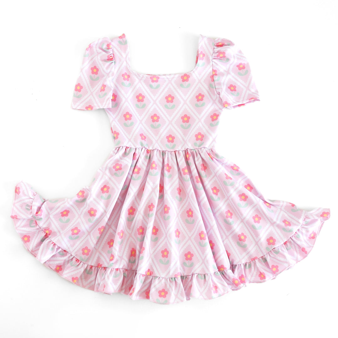 girls' light pink mod twirl dress with white diamond print surrounding and pink daisies