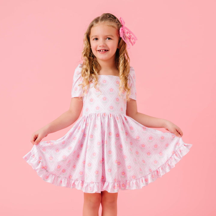 little girl in pastel pink twirl dress with pink daisy design for spring