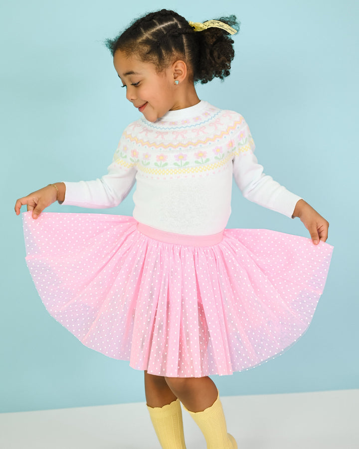 young girl in white spring fair isle sweater, pink utu skort with white dots and yellow knee socks for spring