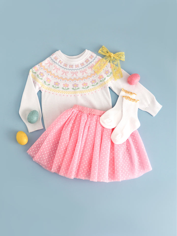 flat lay of girls' spring fair isle sweater with matching pink tulle skort with white dots and sunshine yellow accesories