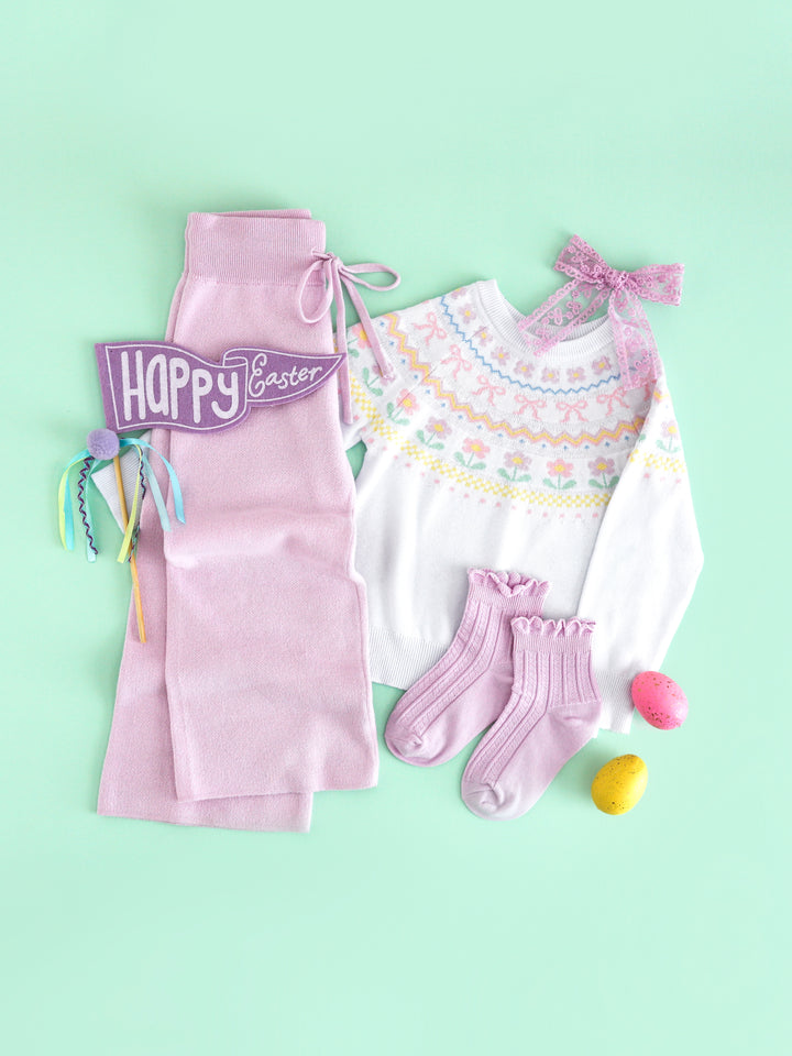 girls' cozy Easter outfit flat lay featuring white fair isle sweater with pastel spring design pared with lavender sweater pants, midi socks and lace hair bow