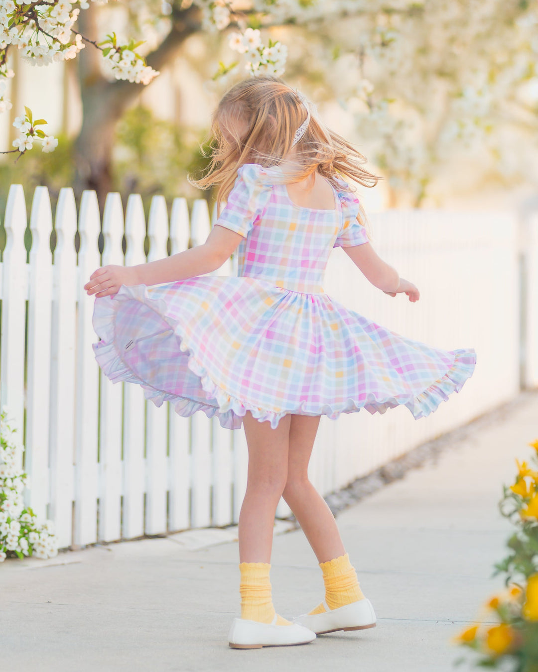 girls twirling in pastel gingham twirl dress with matching pastel scalloped trim knee socks scrunched down