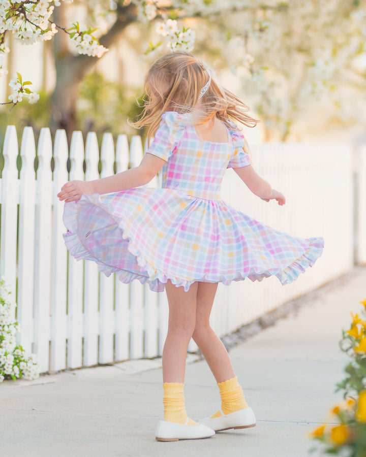 girls twirling in pastel gingham twirl dress with matching pastel scalloped trim knee socks scrunched down