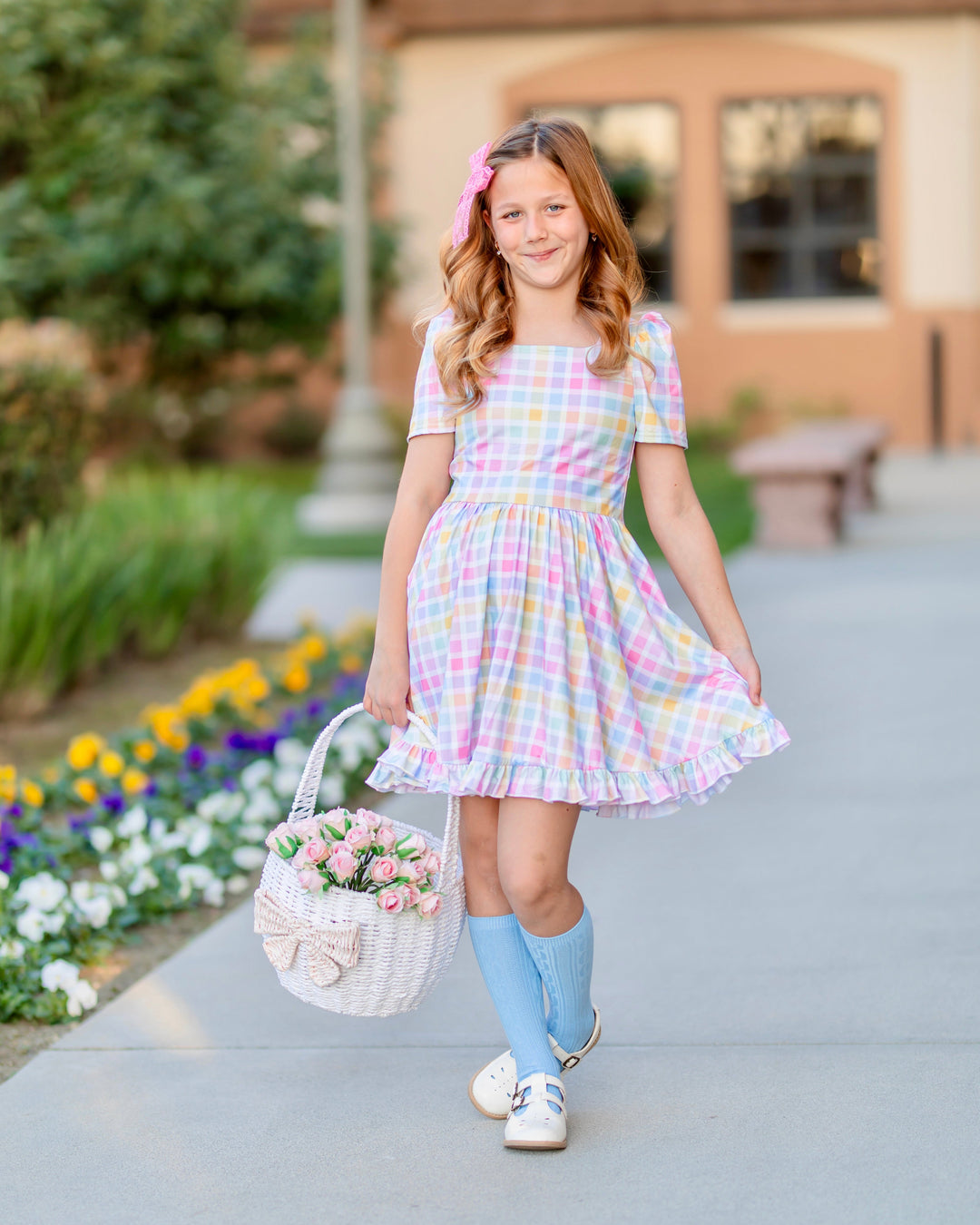 girl holding easter basket with pink roses wearing pastel gingham twirl dress, matching blue cable knit knee socks and pink lace bow