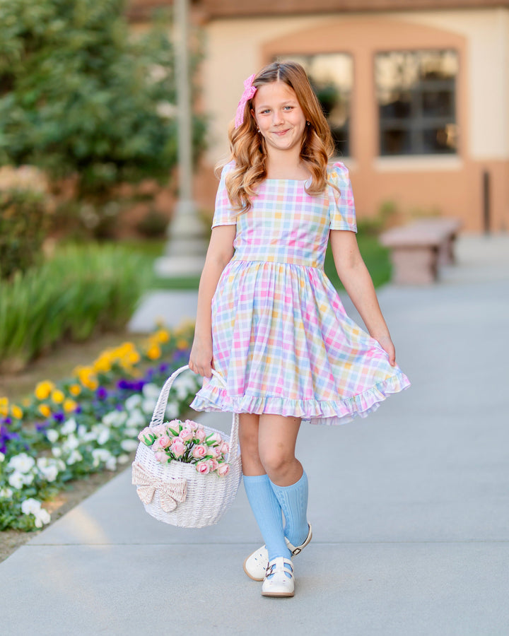 girl holding easter basket with pink roses wearing pastel gingham twirl dress, matching blue cable knit knee socks and pink lace bow