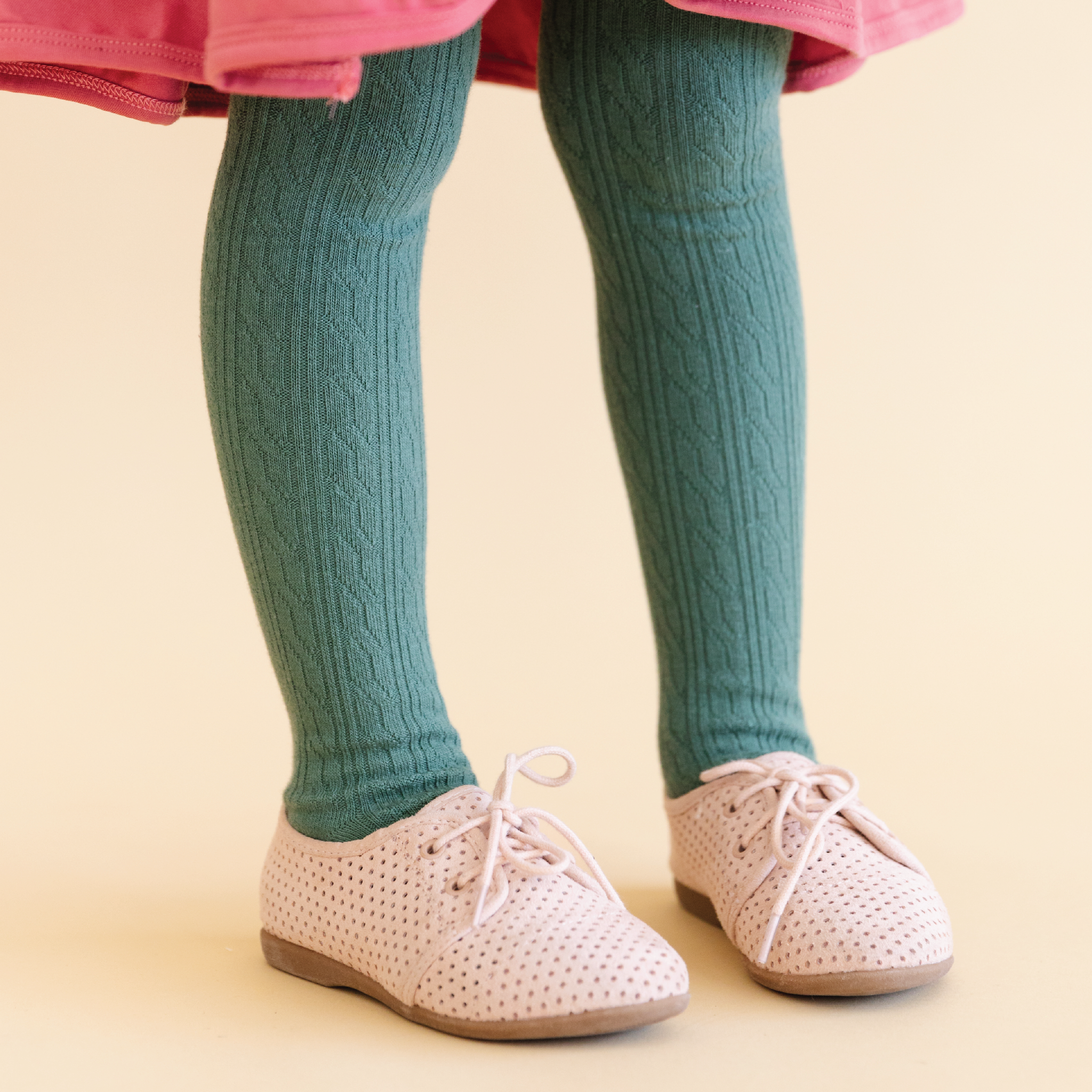 girls legs in spuce green turquoise colored cable knit tights