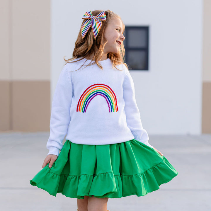 little girl wearing irish green twirl dress with embroidered rainbow sweater over top
