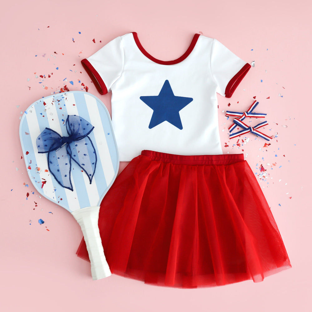 girls white fitted t-shirt with blue star design and red binding paired with red tutu shorts and matching hair bows for 4th of July
