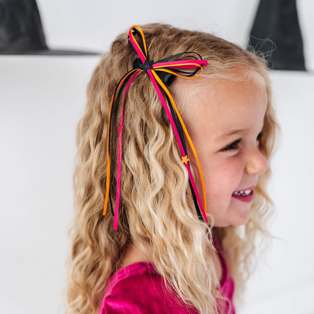 young girl with tri-color ribbon hair bow in black, pink and orange with tiny star embellishments to match Halloween collection 