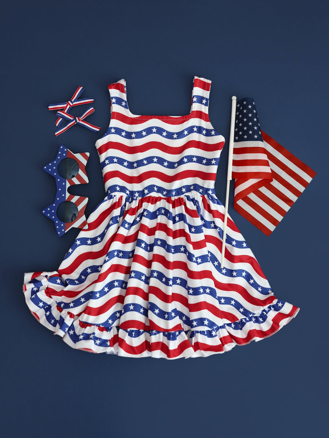flatlay of girls red white and blue stars and stripes sleeveless dress and matching accessories
