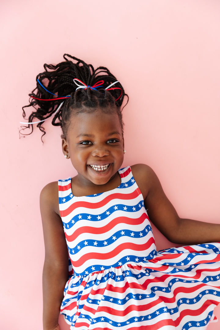 girl wearing red white and blue stars and stripes sleeveless dress and americana ponytail bow