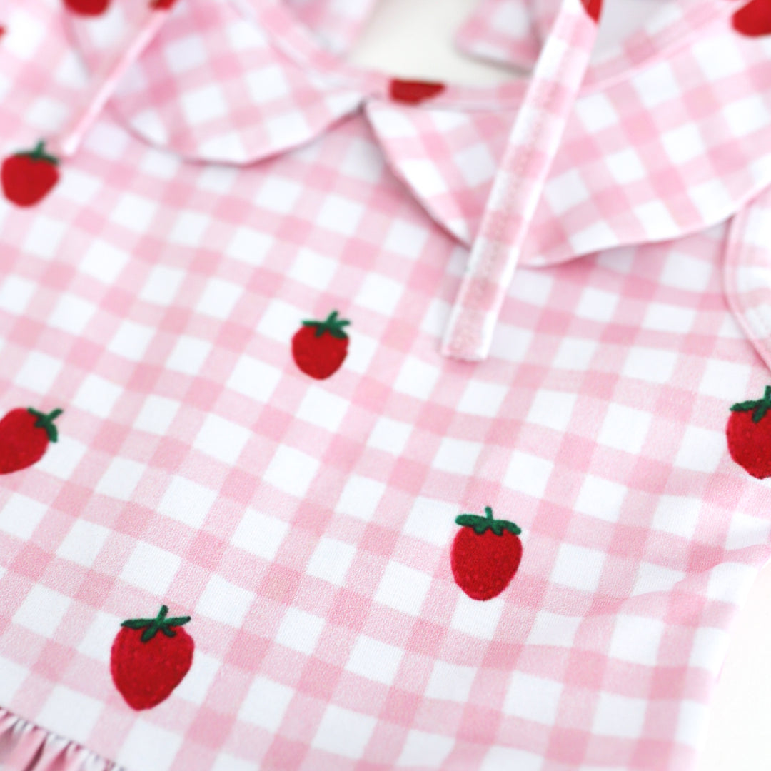 detail photo of pink and white gingham print with scattered strawberries on girl's summer twirl dress