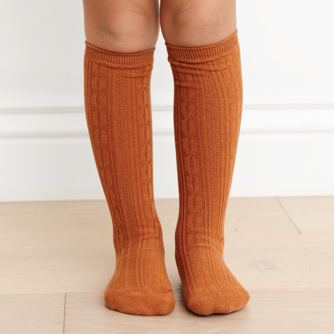 girls legs wearing cognac brown cable knit knee high socks