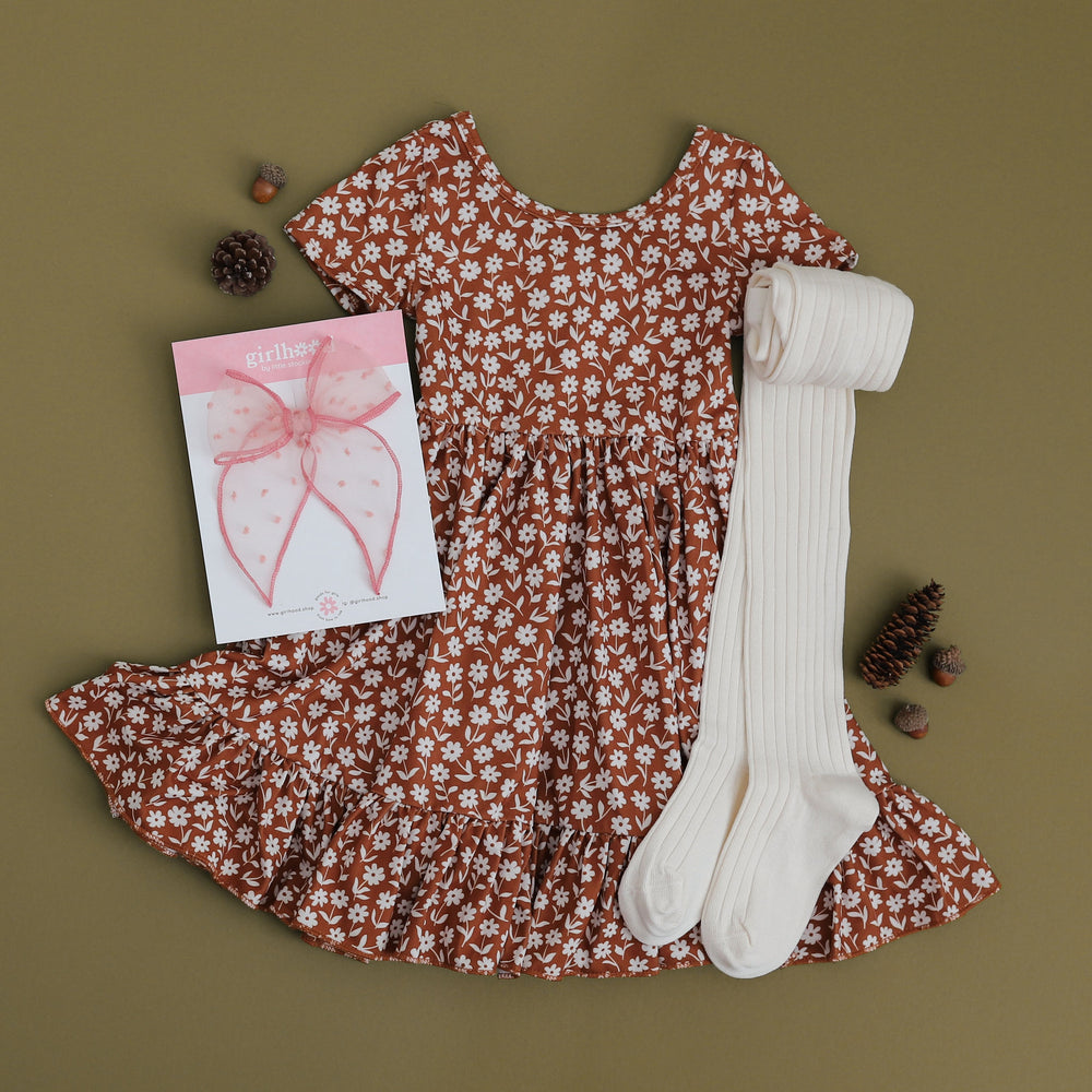 neutral toned micro floral print dress for little girls styled with matching ivory ribbed cotton tights and blush pink hair bow