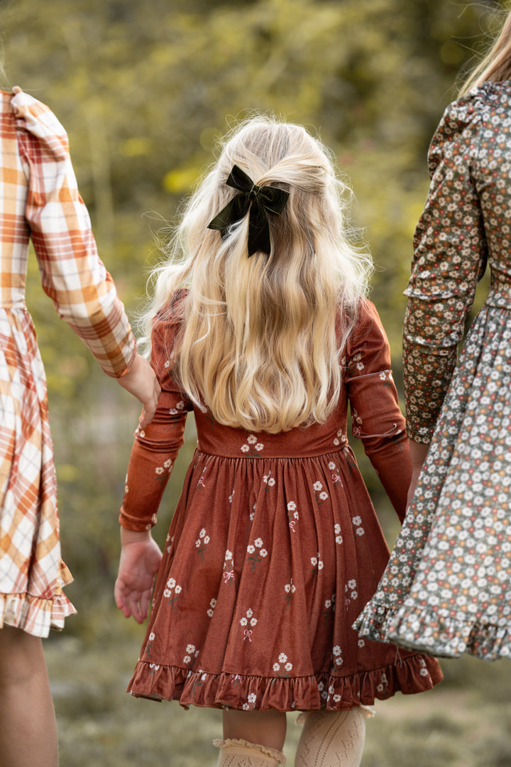 girls in fall velvet dress with golden brown floral at the center paired with olive green velvet hair bow