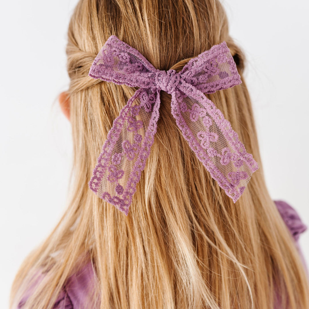 close-up of girls hair with purple lace hair bow clip