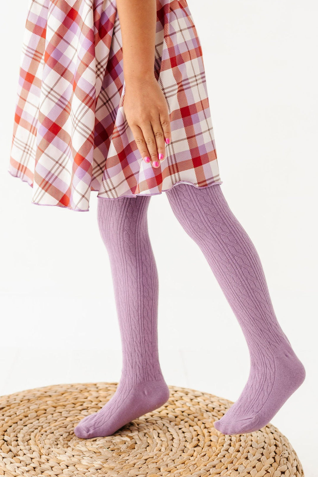 girl wearing purple cable knit tights with rust and purple plaid dress