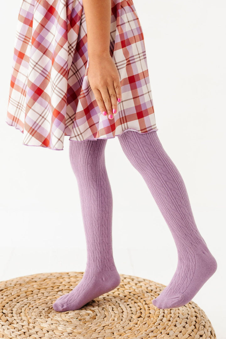 girl wearing purple cable knit tights with rust and purple plaid dress