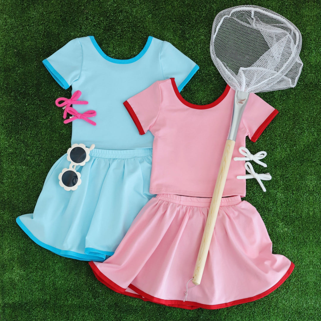 styled flay lay of girls' summer sets with matching t-shirts and skorts in blue and pink
