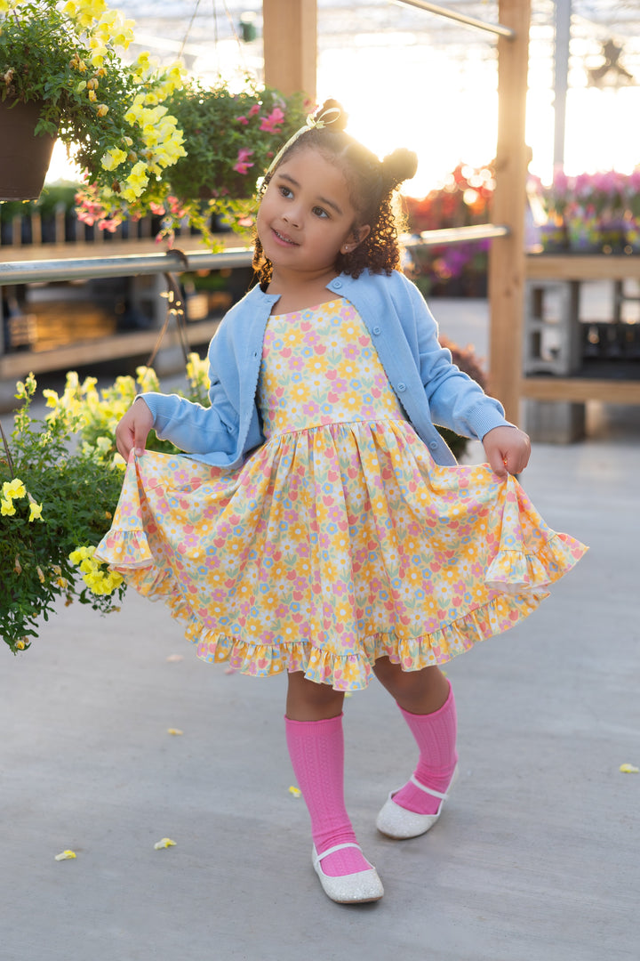 little girl in yellow spring floral twirl dress, hot pink knee highs and matching blue sweater with scallop edge detail