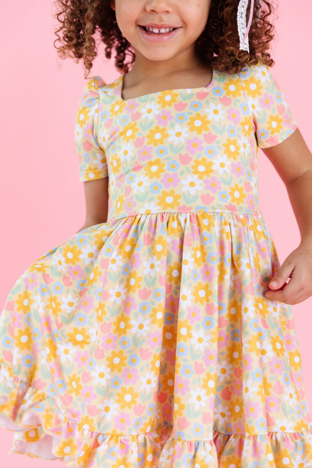 close up of girl wearing pastel yellow square neck twirl dress with spring flower print