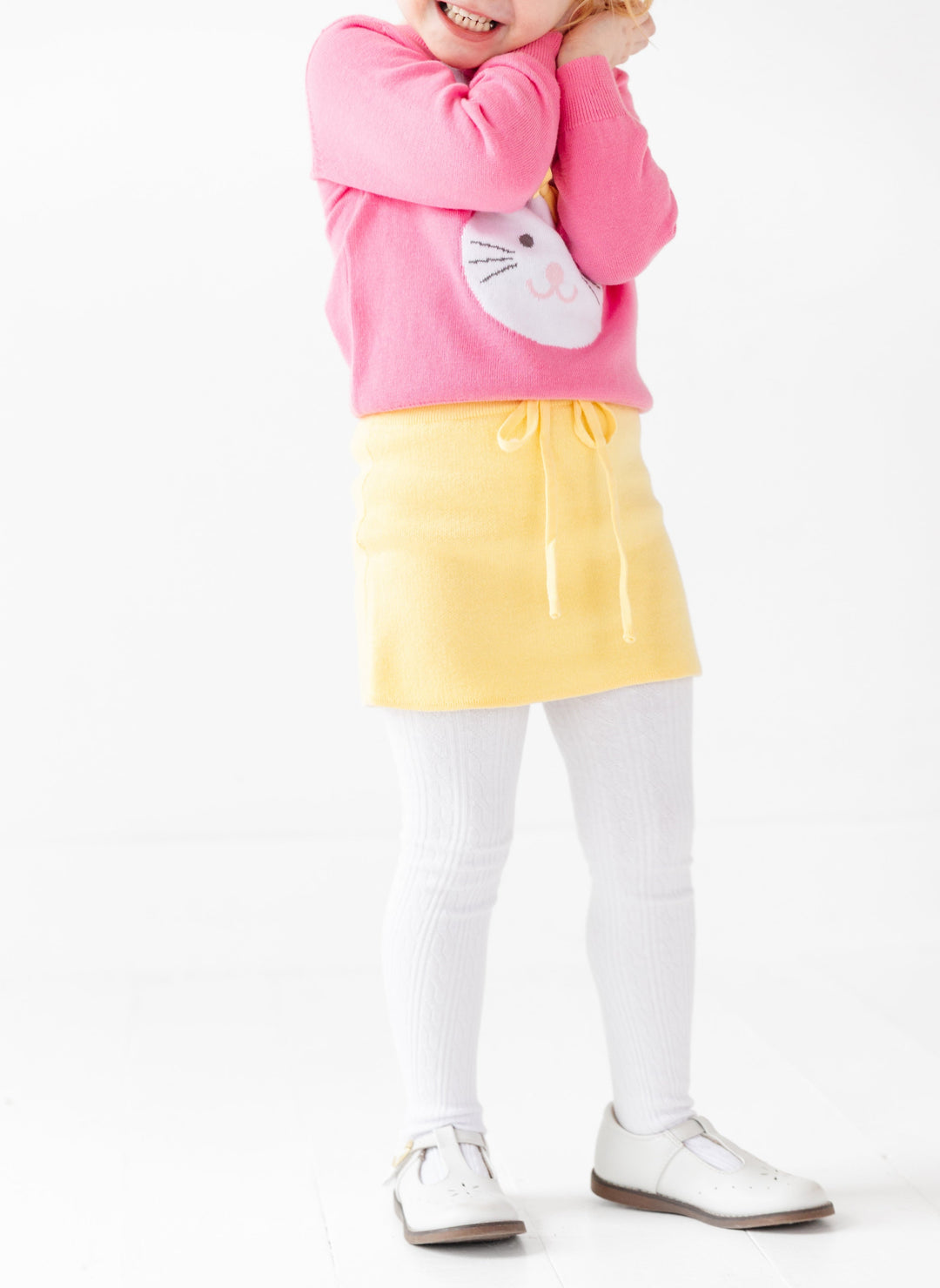 girls yellow knit skirt with drawstring paired with pink bunny sweater and white cable knit tights