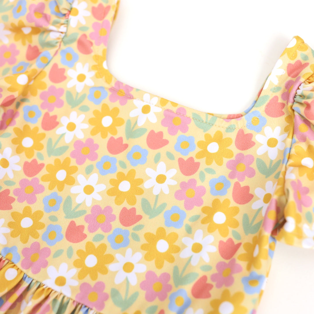 close up of girl's pastel yellow square neck twirl dress with spring flower print