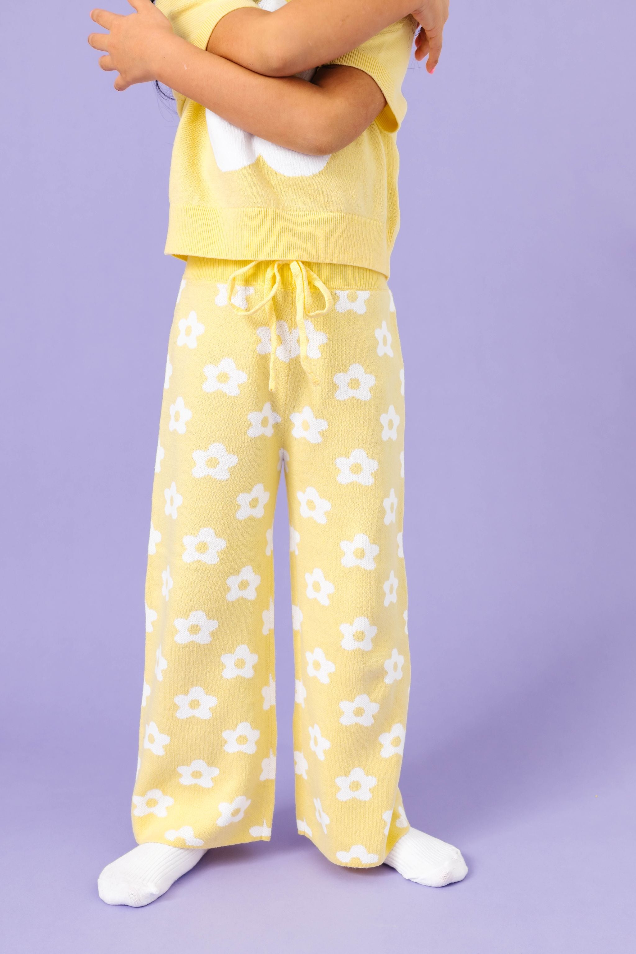 little girl wearing sunny yellow cotton knit sweater pants with drawstring waistband and all over white flower design for spring